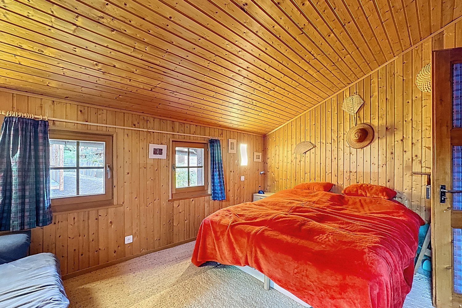 Pièce sous les pans du toit, entièrement lambrissée, avec lit et couchages d'appoint.