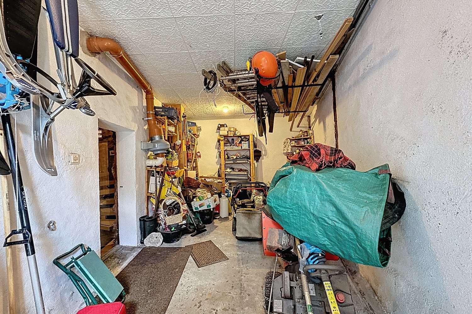 Garage du chalet avec râteliers à skis au mur, étagères et matériel de sport.